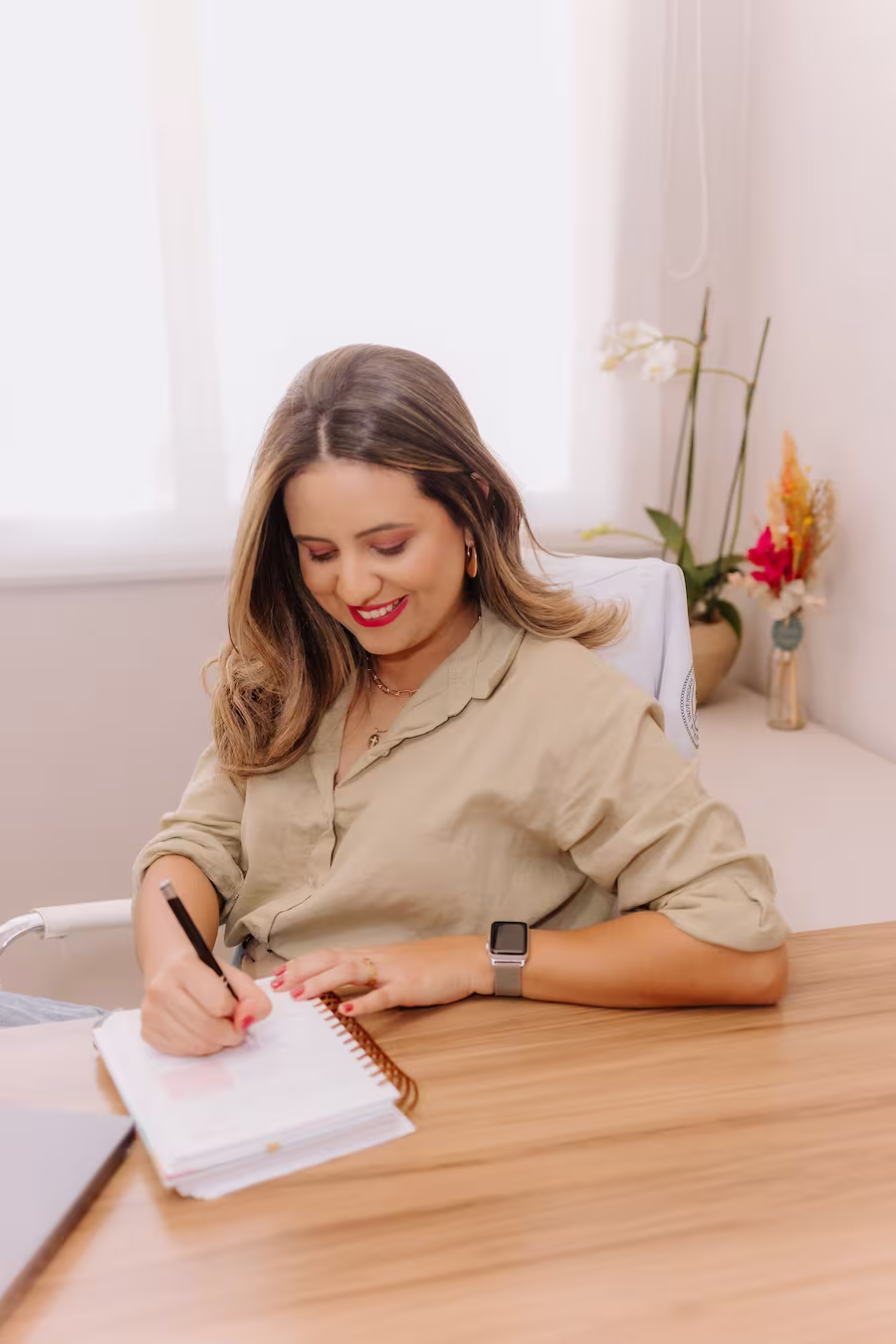 Mãe amamentando bebê em poltrona com luz natural durante consulta online de amamentação